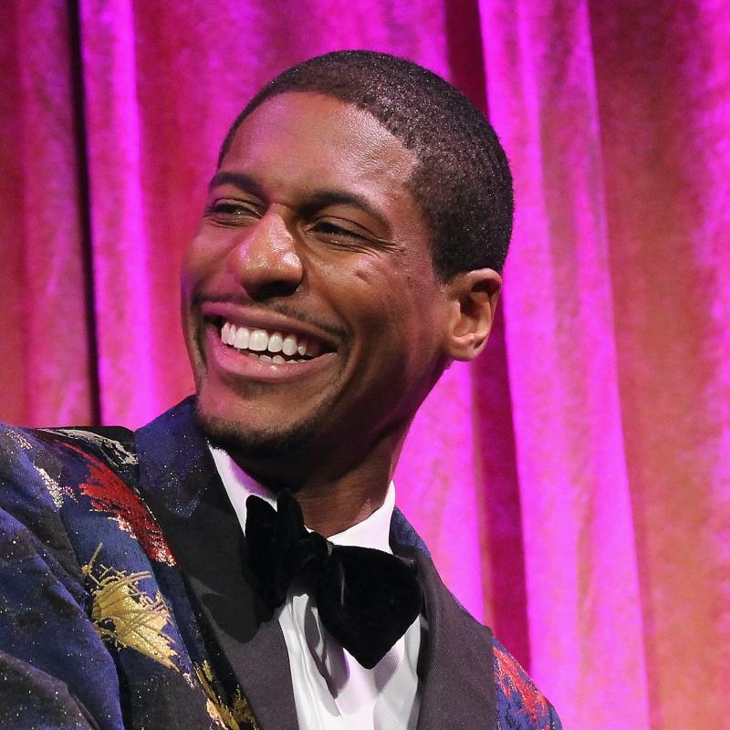 Musician Jon Batiste plays the piano while smiling