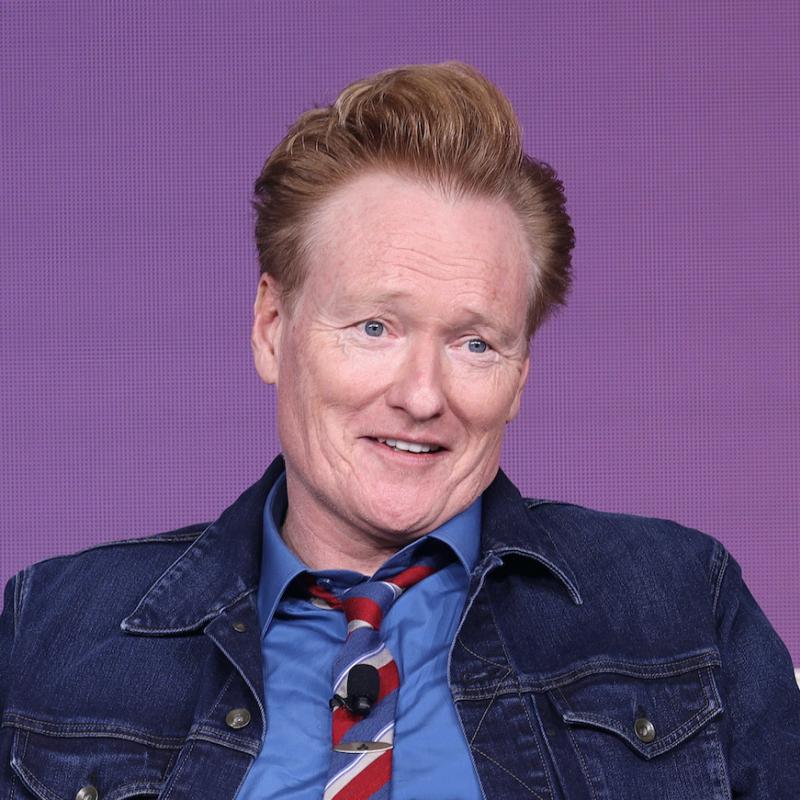 Comedian and TV host Conan O'Brien smiles while seated