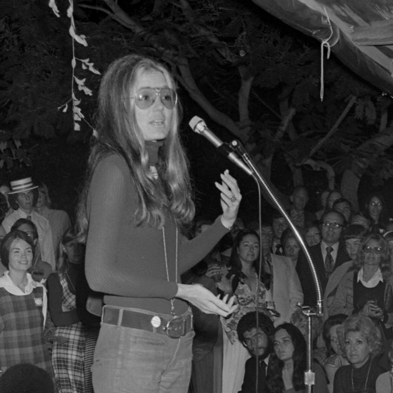 Black and white image of Gloria Steinem addressing a crowd at a fundraiser and rally